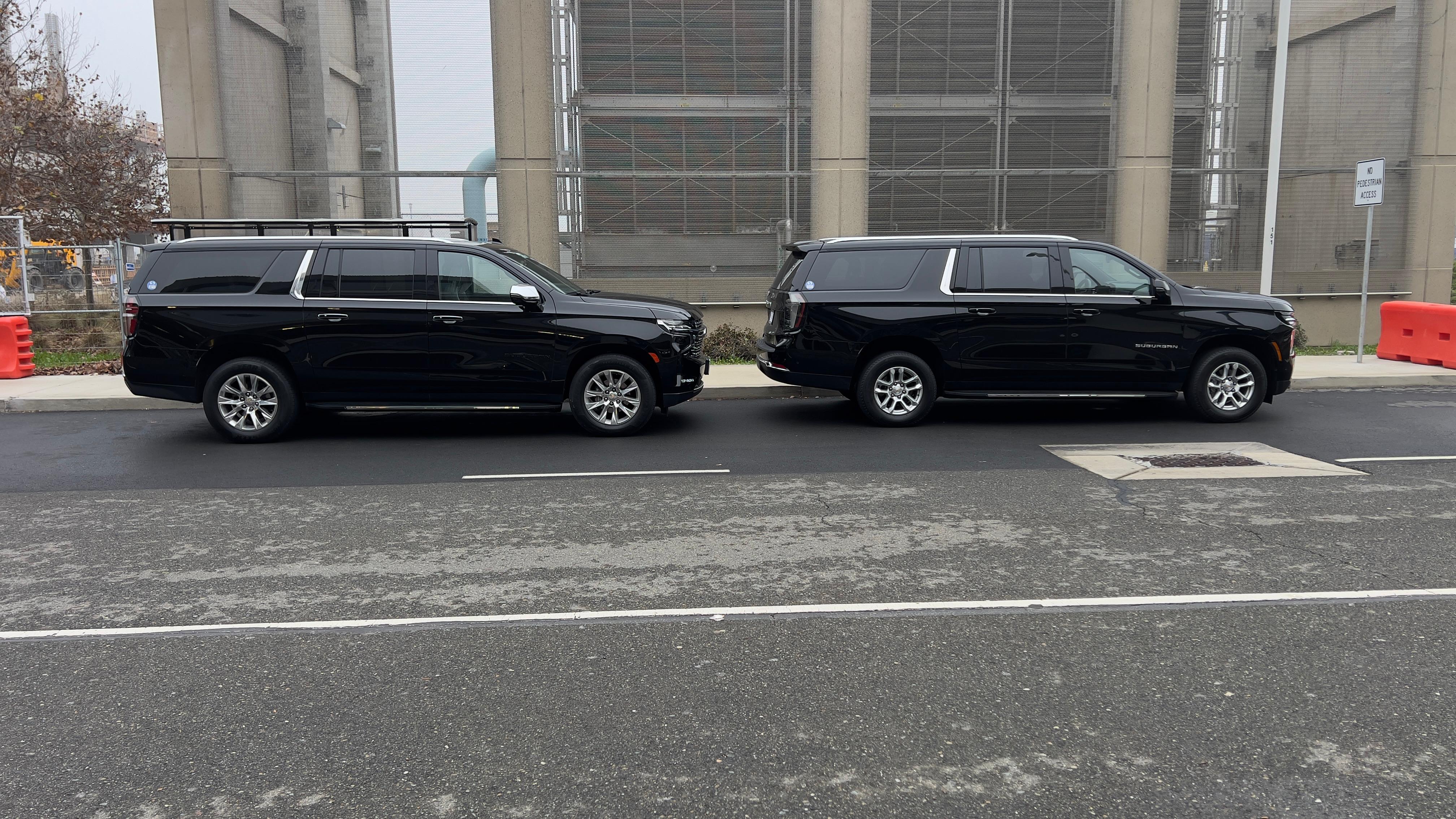 Two S&T Transportation Chevrolet Suburban SUVs parked side by side